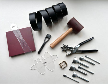 Collection of leatherworking tools and materials on a white surface