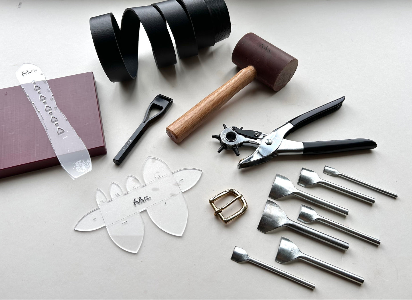 Collection of leathercraft tools and supplies on a white surface