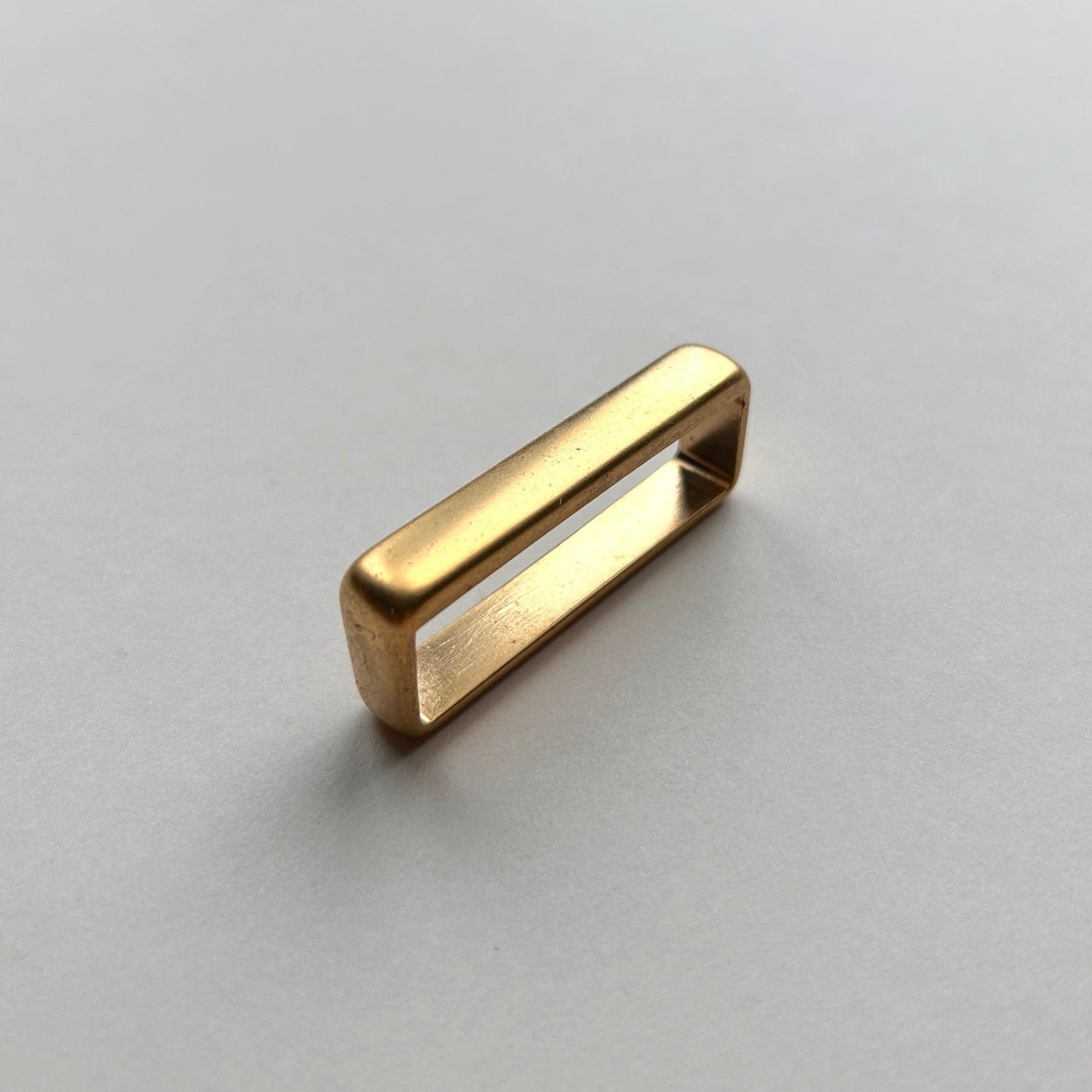 Gold metal brass belt loop keeper on a white background