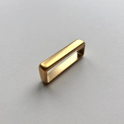 Gold metal brass belt loop keeper on a white background