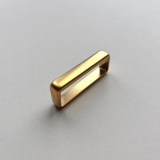 Gold metal brass belt loop keeper on a white background