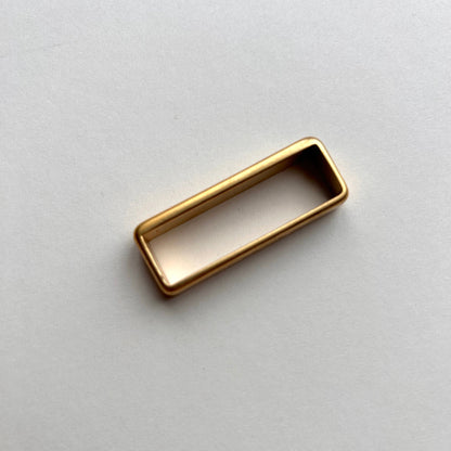 Gold metal brass belt loop keeper on a white background