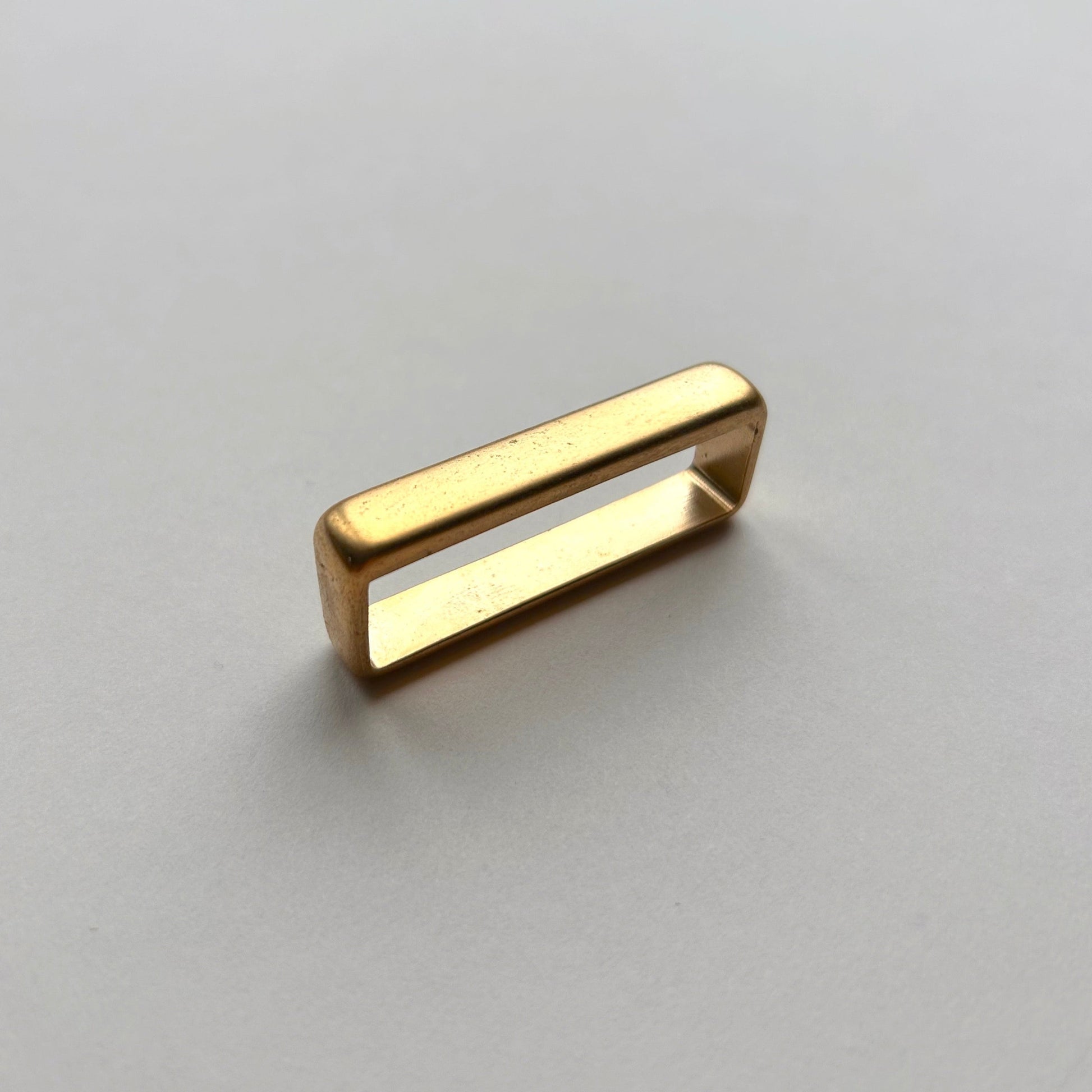 Gold metal brass belt loop keeper on a white background