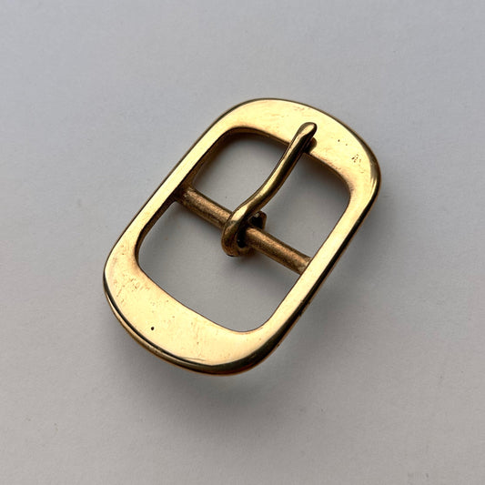 Brass centre bar buckle on grey background