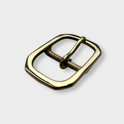 Gold coloured brass metal buckle with a centre bar on a light grey background.