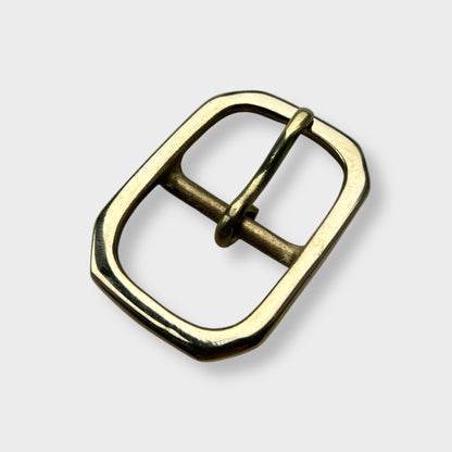 Gold coloured brass metal buckle with a centre bar on a light grey background.