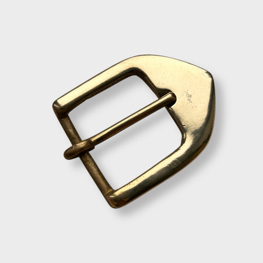 Gold coloured brass metal buckle on a light grey background.