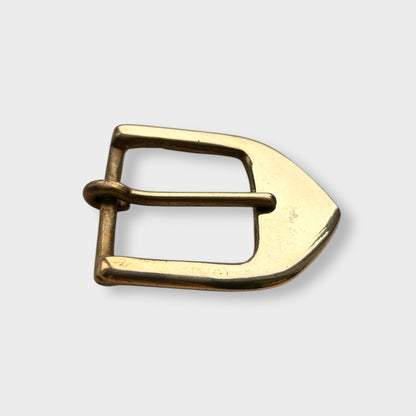 Gold coloured brass metal buckle on a light grey background.