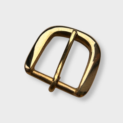 Gold coloured brass metal buckle on a light grey background.