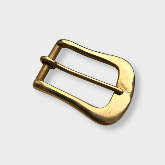 Gold coloured brass metal buckle on a light grey background.