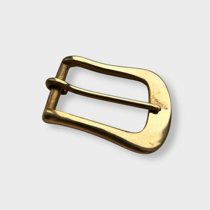 Gold coloured brass metal buckle on a light grey background.