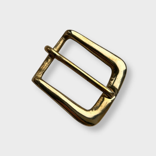 Gold coloured brass metal buckle on a light grey background.