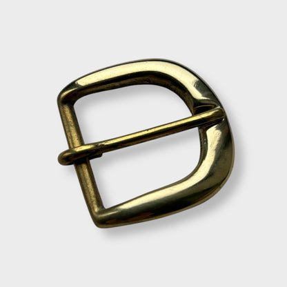 Gold coloured brass metal buckle on a light grey background.