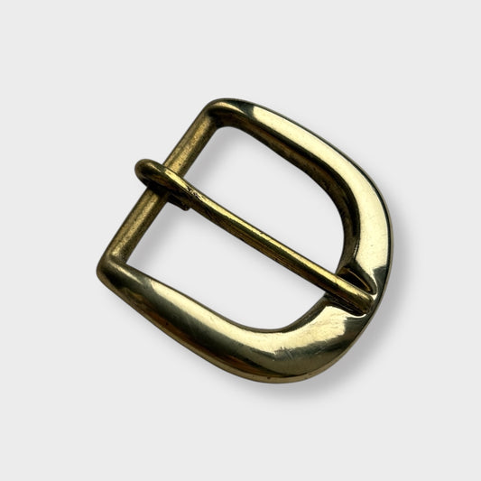 Gold coloured brass metal buckle on a light grey background.