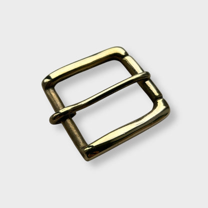 Gold coloured brass metal buckle on a light grey background.