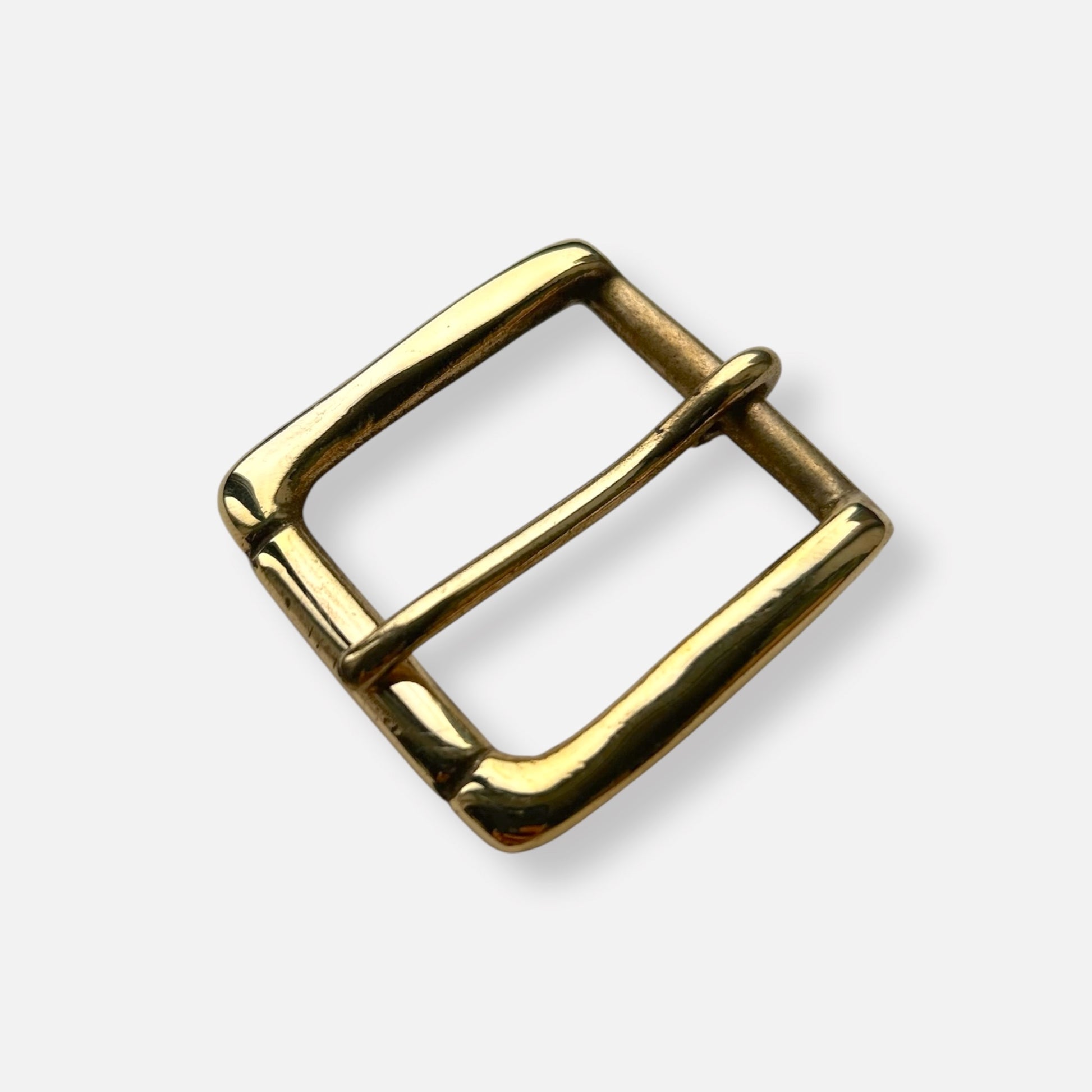 Gold coloured brass metal buckle on a light grey background.
