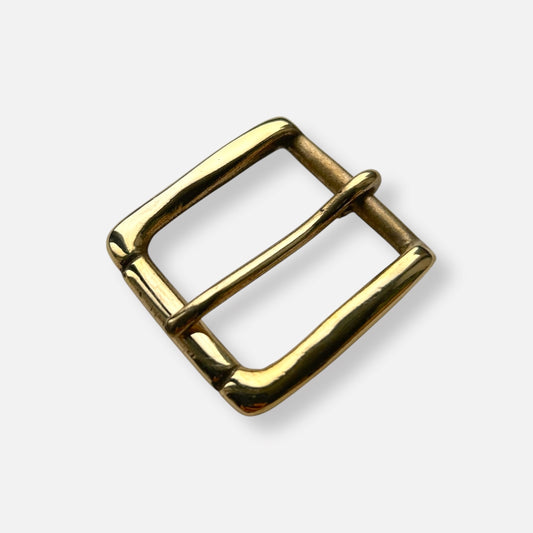 Gold coloured brass metal buckle on a light grey background.
