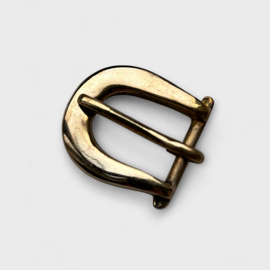 Gold metal buckle on a light gray background