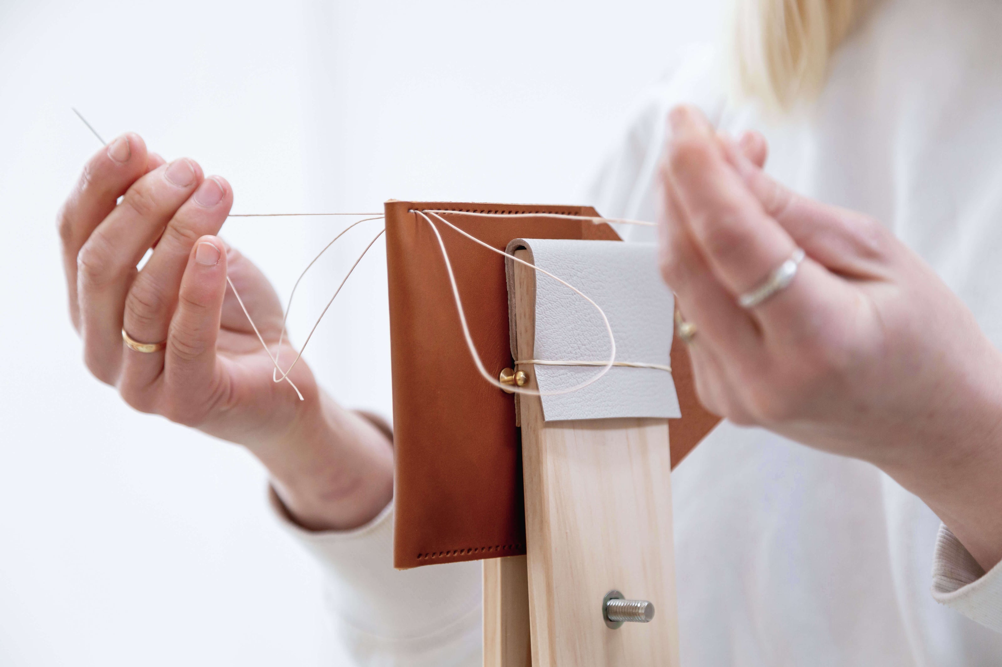 leatherworkers hand sewing leather using a stitching pony