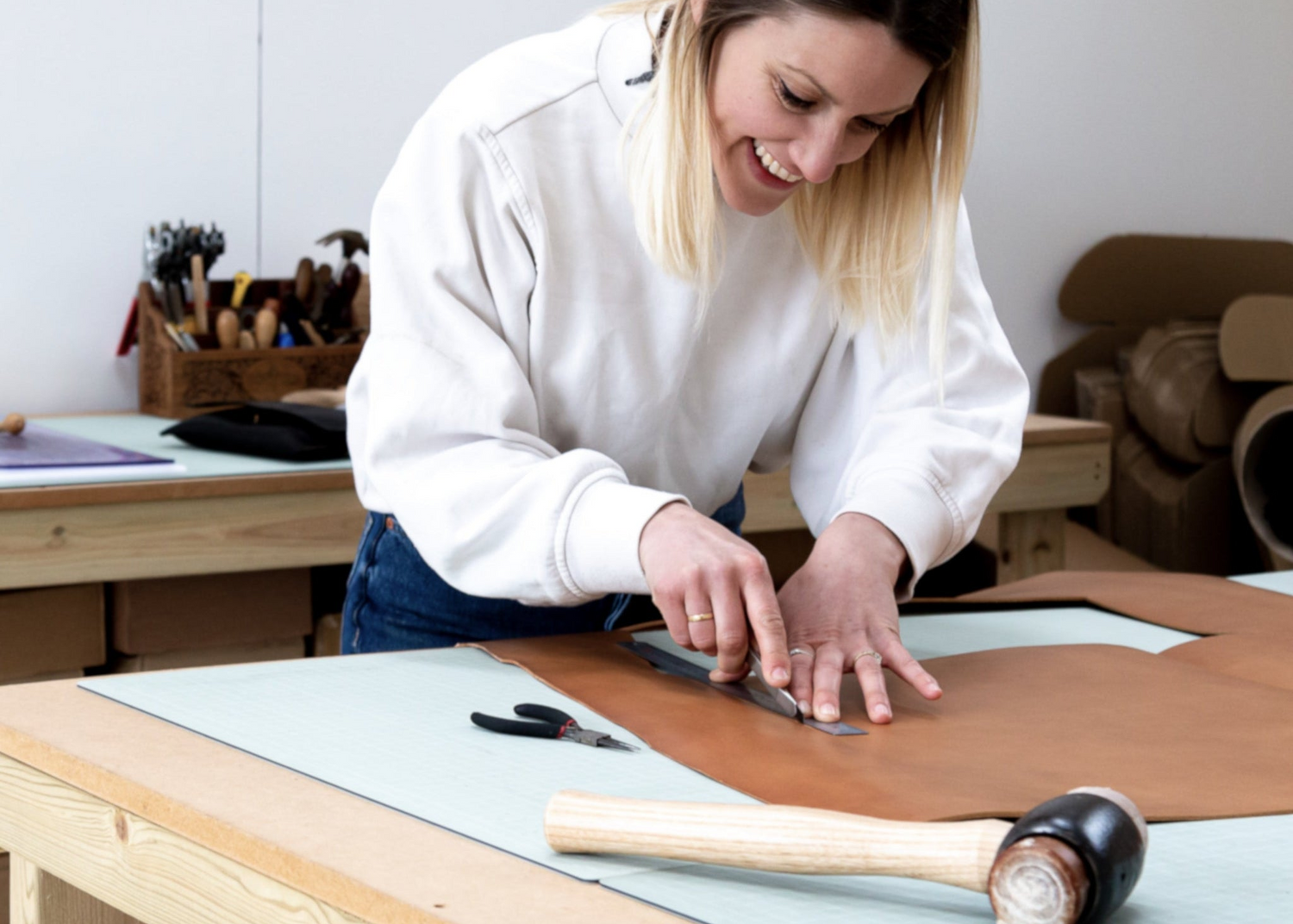 Becky from British Leather Supplies working with leather on a table in a workshop setting