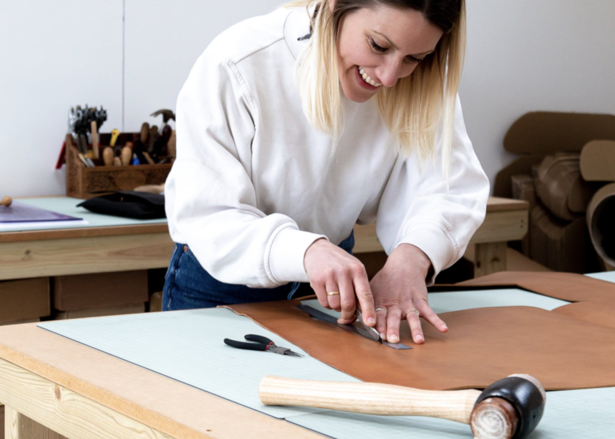 Becky from British Leather Supplies working with leather on a table in a workshop setting
