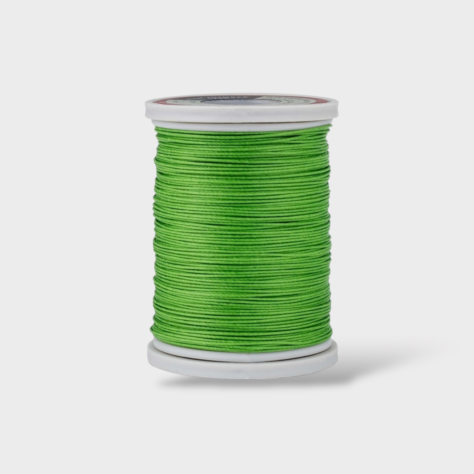 Spool of green thread on a white background