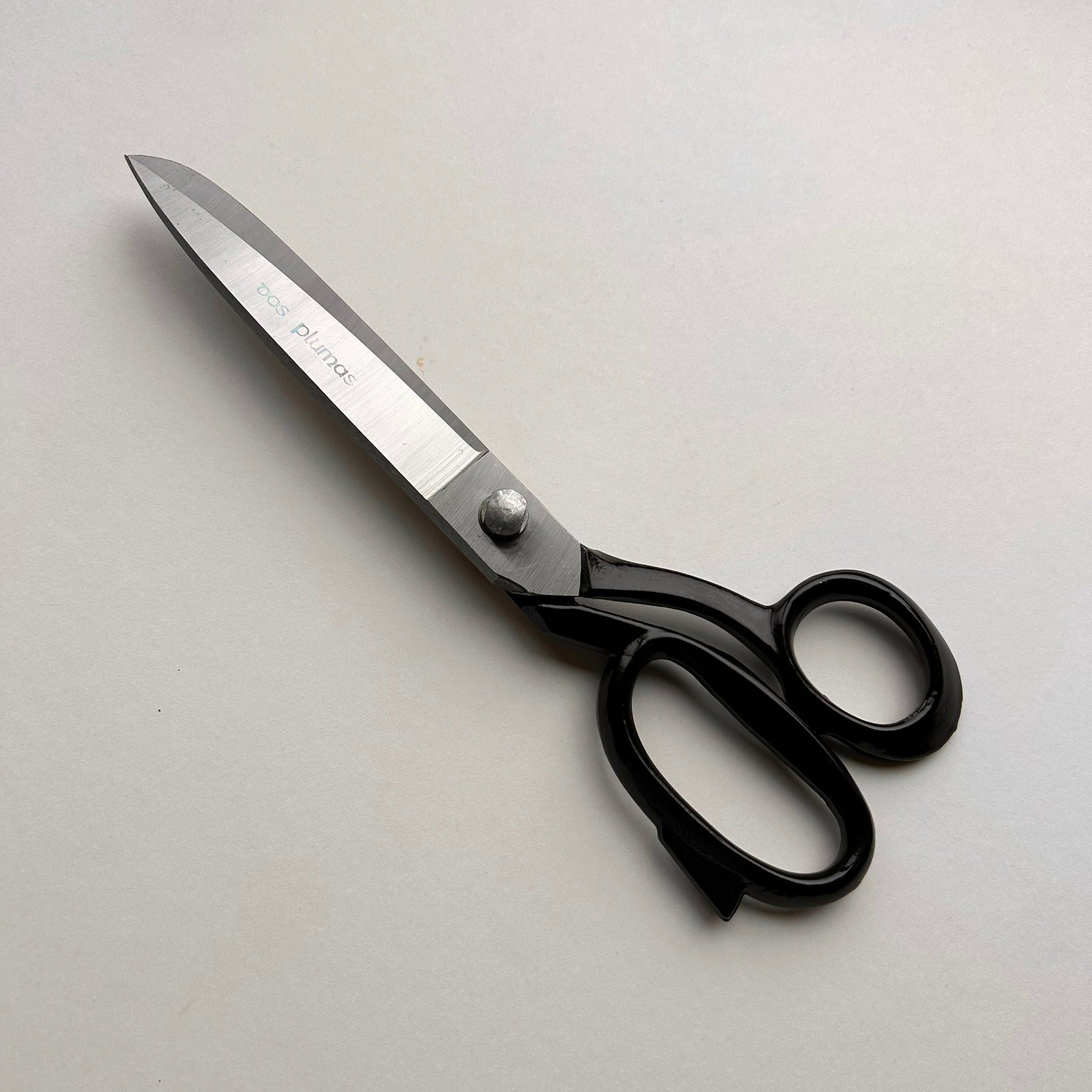 Pair of leather scissors with black handles on a white background
