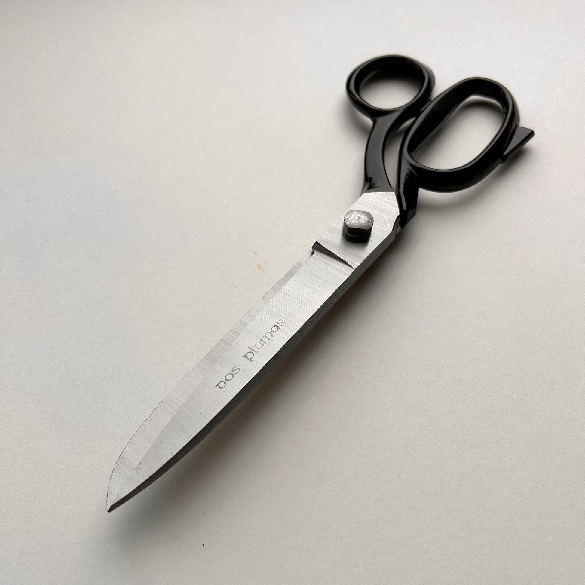 Pair of leather scissors with black handles on a white background
