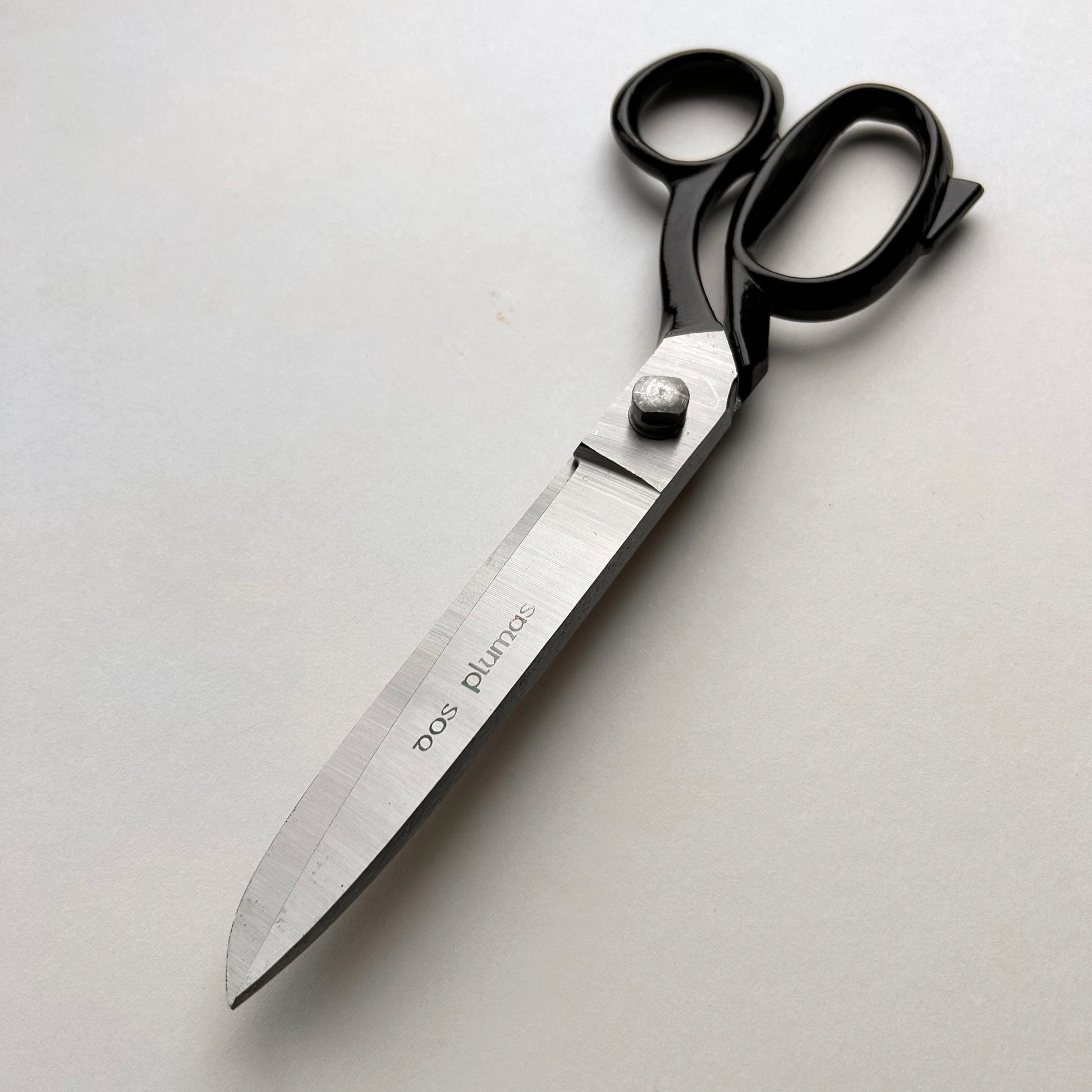 Pair of leather scissors with black handles on a white background