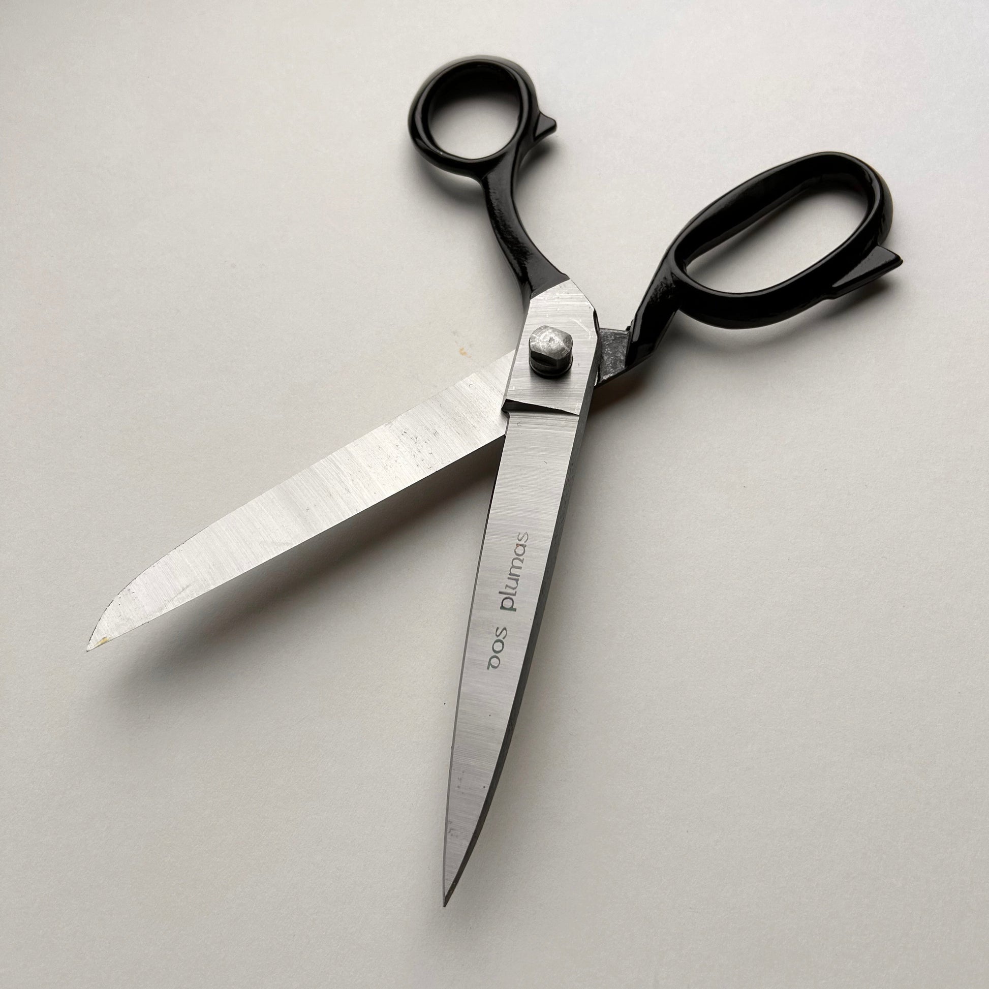 Pair of leather scissors with black handles on a white background