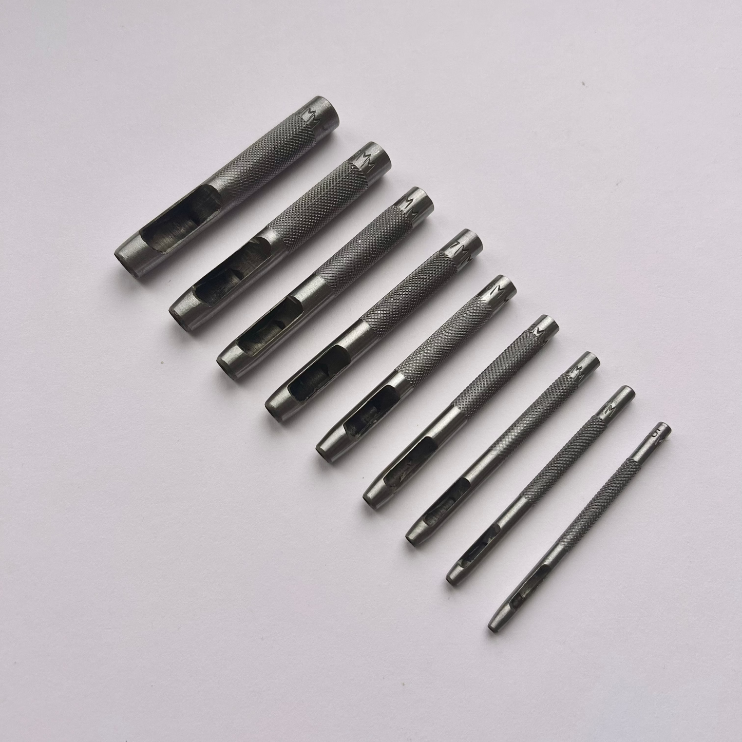 Set of metal leather drive punch tools on a grey background