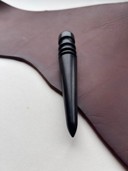 Black wooden leather burnishing tool on a brown leather surface