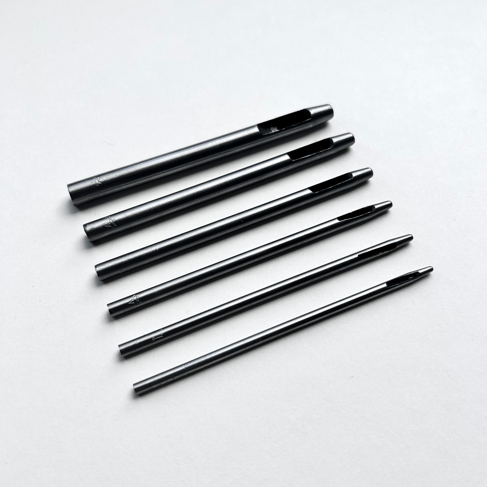 Set of six leather hole punch tools on a white background