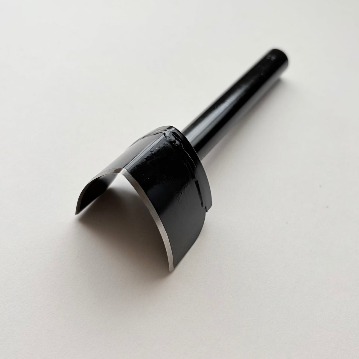 A black metal strap end punch with a long shank, photographed on a plain light grey background.