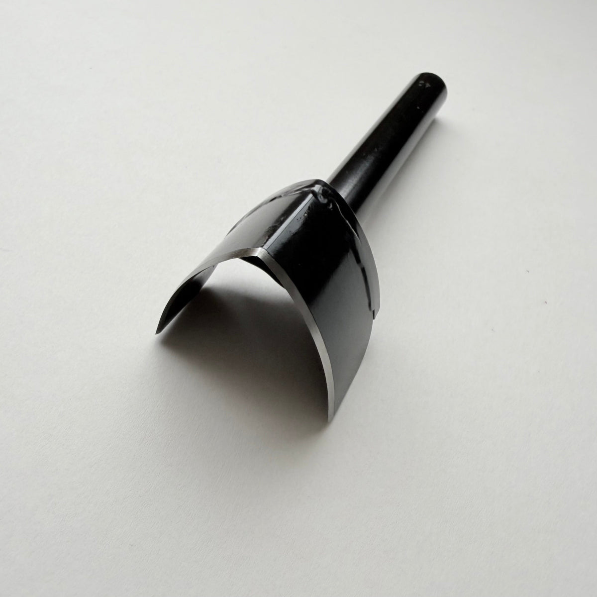 A black metal strap end punch with a long shank, photographed on a plain light grey background.