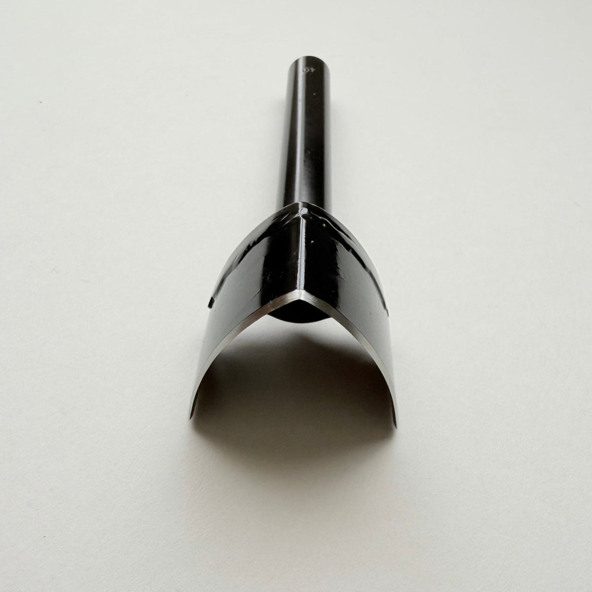 A black metal strap end punch with a long shank, photographed on a plain light grey background.