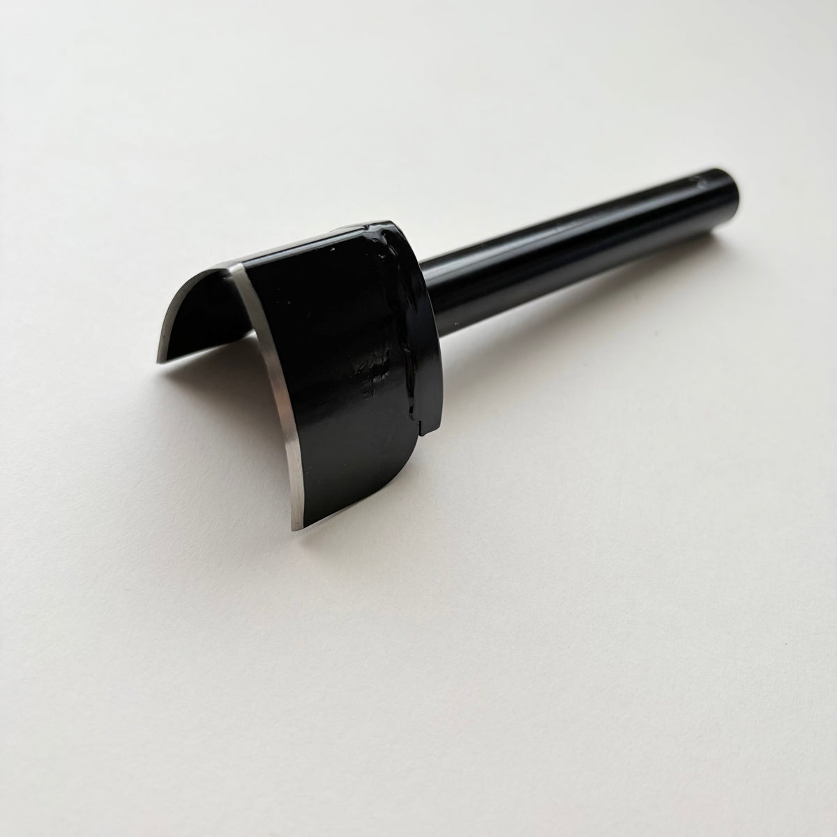 A black metal strap end punch with a long shank, photographed on a plain light grey background.
