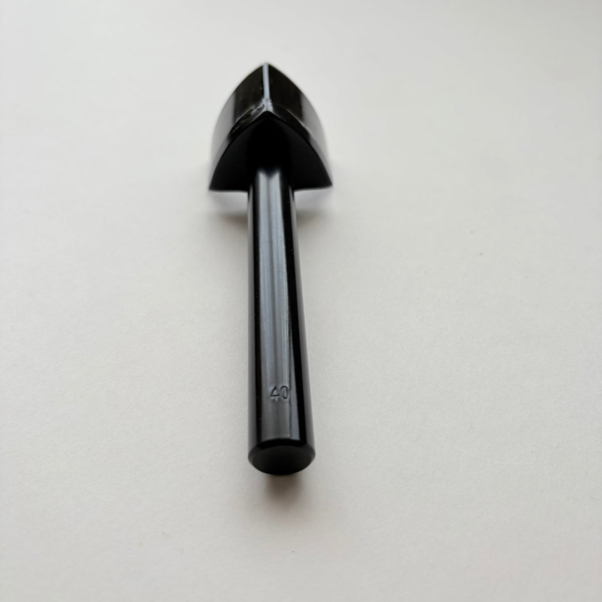 A black metal strap end punch with a long shank, photographed on a plain light grey background.