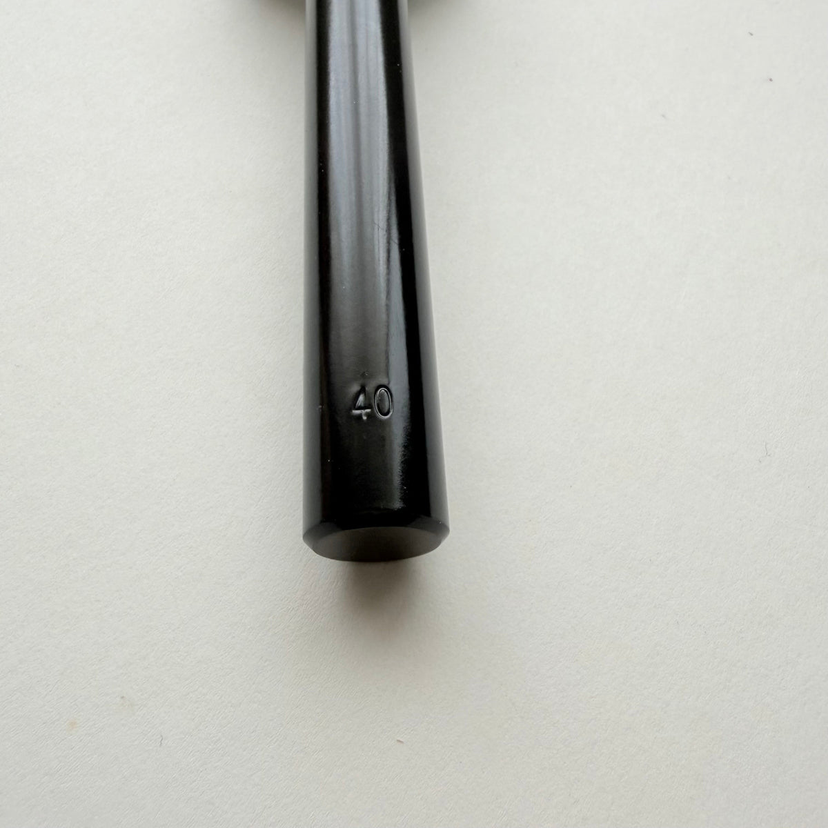 A black metal strap end punch with a long shank, photographed on a plain light grey background.