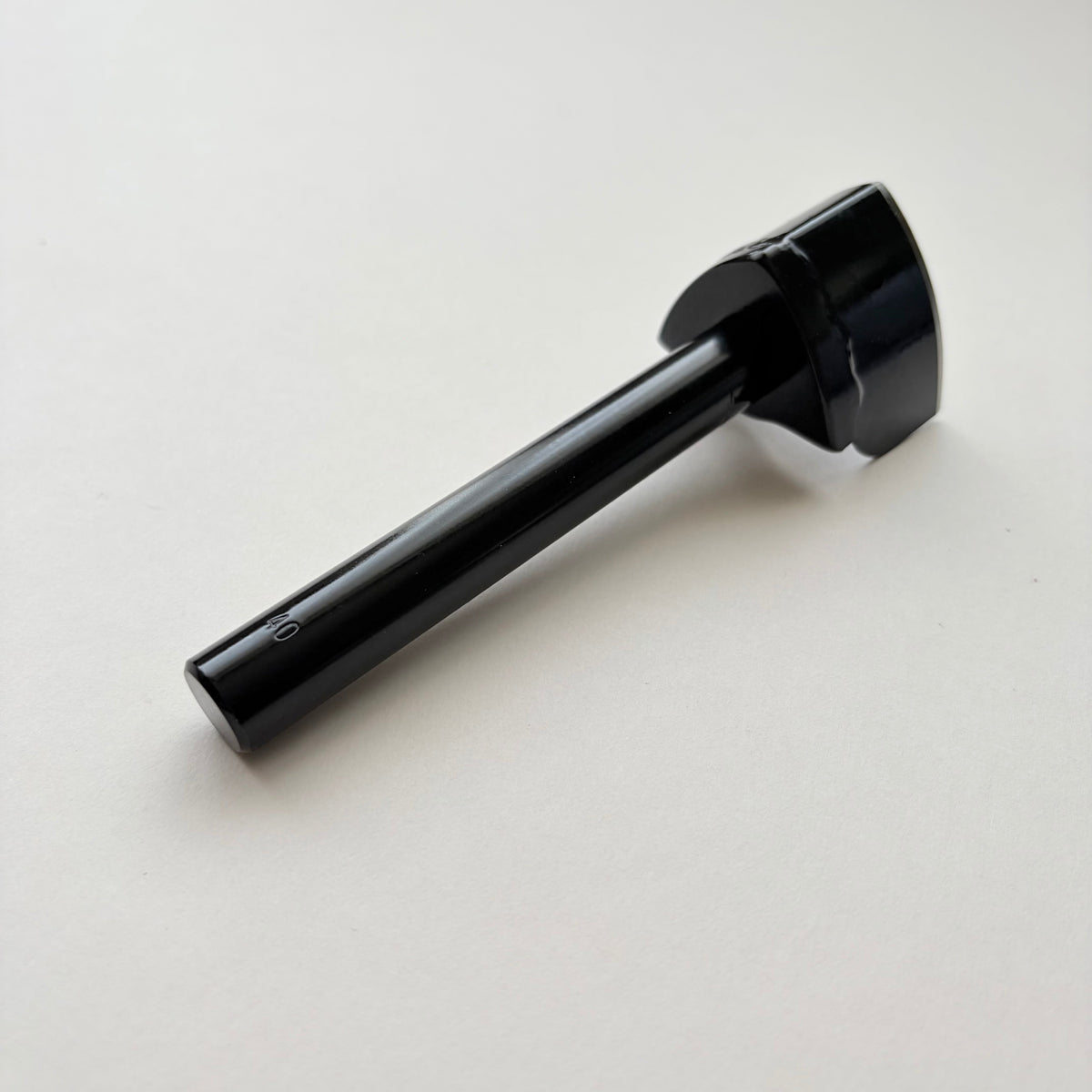 A black metal strap end punch with a long shank, photographed on a plain light grey background.