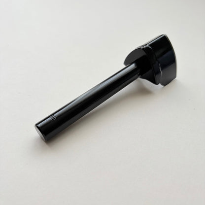 A black metal strap end punch with a long shank, photographed on a plain light grey background.