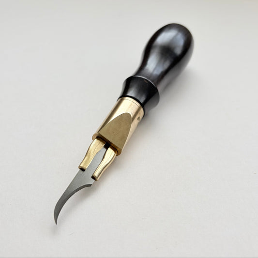 A leatherworking or carving tool with a black wooden handle, brass collar, and curved steel blade, shown on a plain light background.