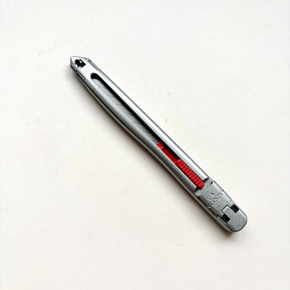 A silver Glanz utility knife with a red sliding scale indicator, shown diagonally on a plain off-white background.