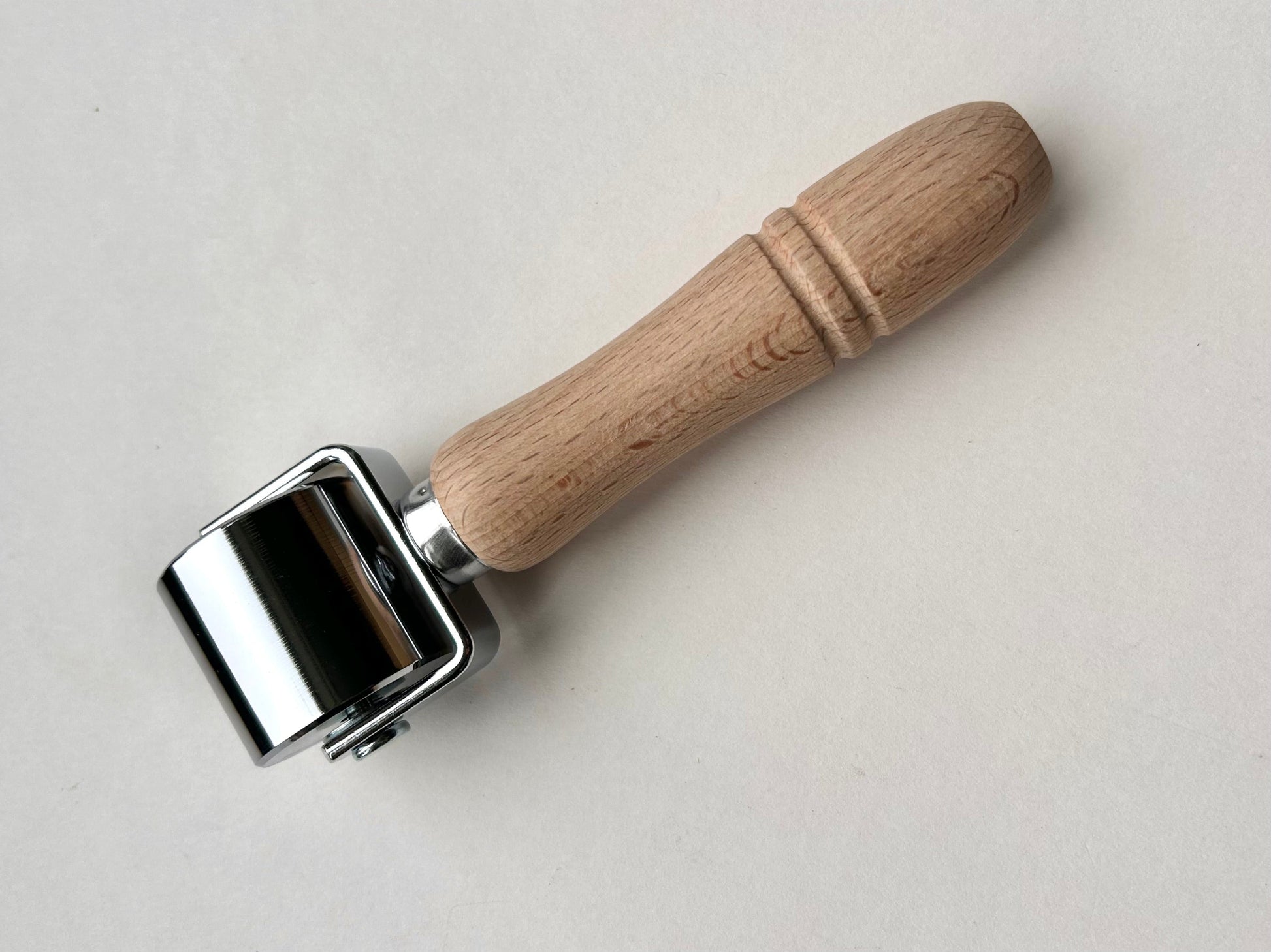 Metal roller with wooden handle on a light gray background