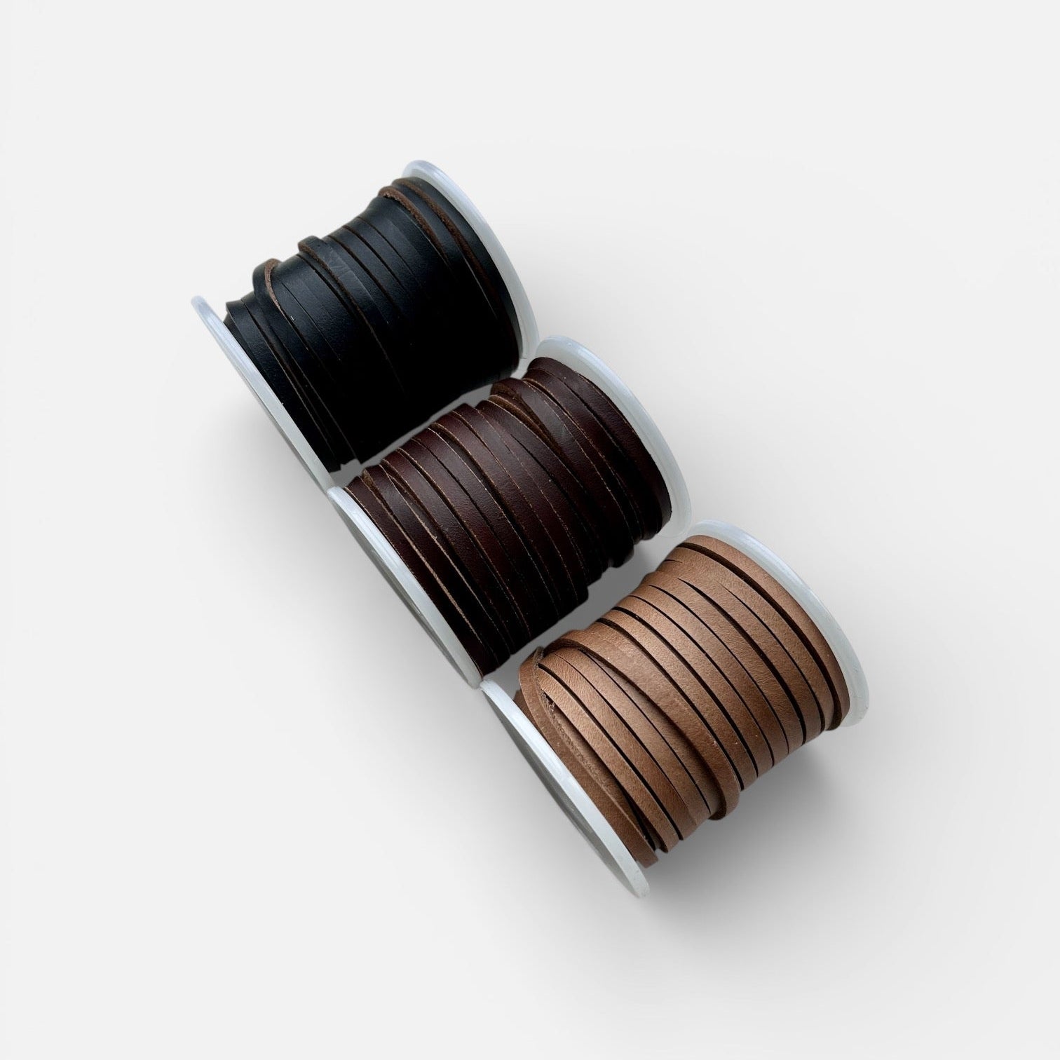 Spools of Horween Leather Thonging Lace Brown, Black and Natural on a white background