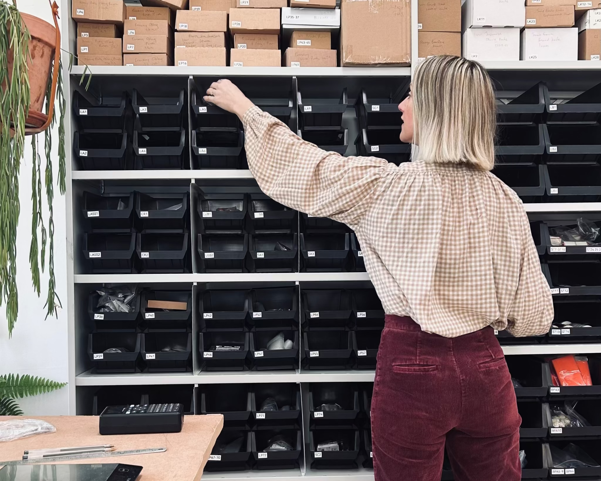 Person reaching for a box on a shelf in the British Leather Supplies studio.