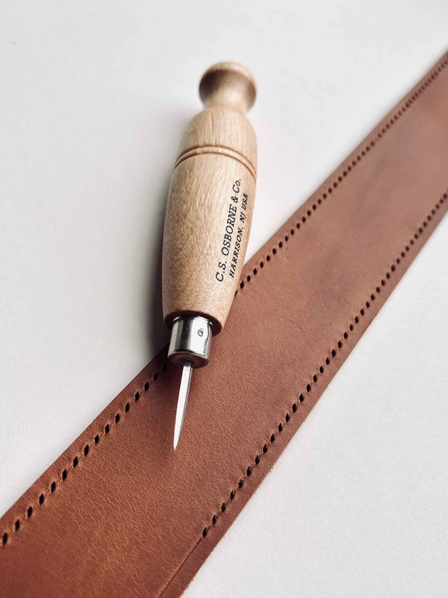 Leather tool with wooden handle on a piece of brown leather