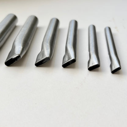 Six metallic oblong punches for leather on a white background