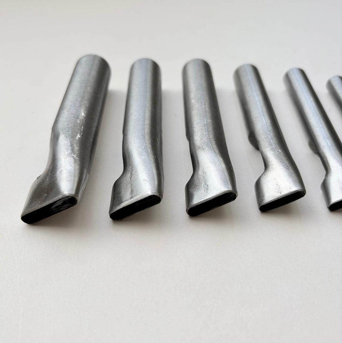 Six metallic oblong punches for leather on a white background
