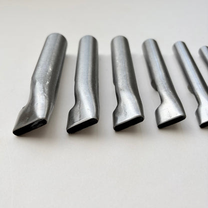 Six metallic oblong punches for leather on a white background